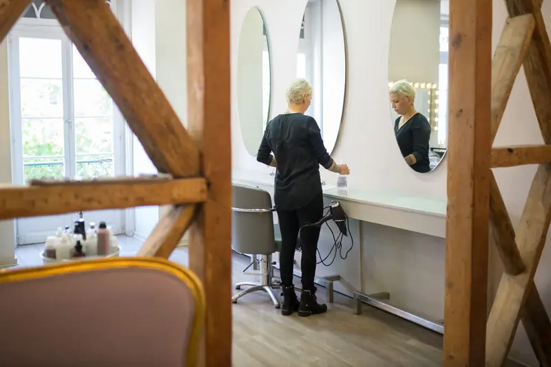 Kapster zet haar werkplek klaar voor de volgende klant in een rustige salon met ronde spiegels.
